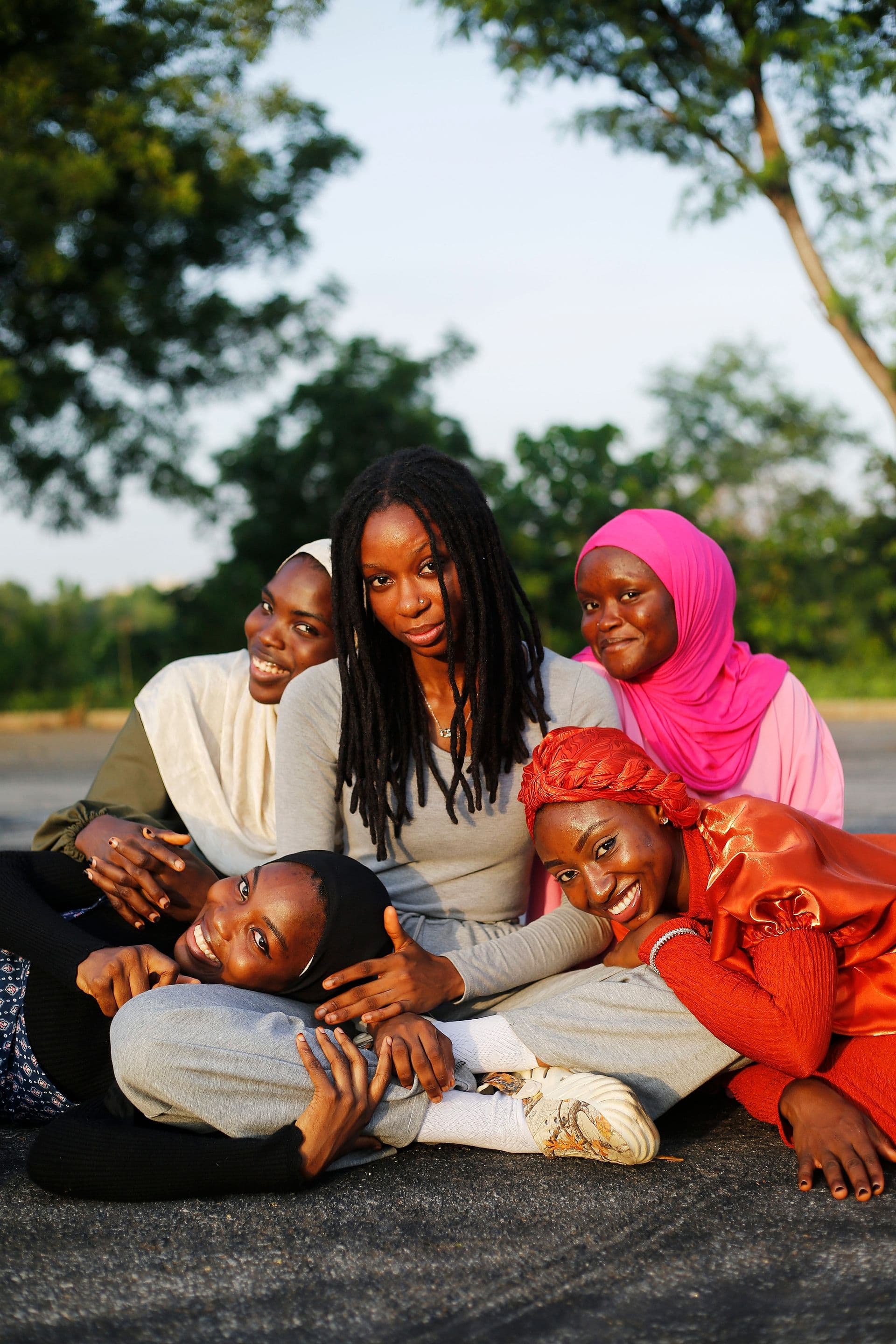 Five friends sitting close together outdoors at golden hour, smiling